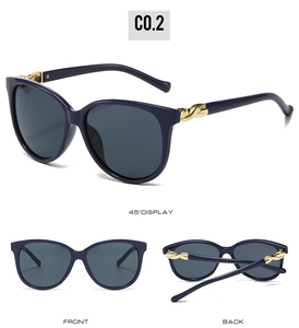 Detail of navy blue oversized sunglasses featuring gold twisted temple accents and grey lenses