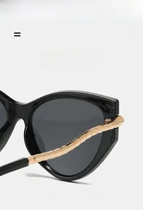 Detail of cat eye sunglasses showing golden metal chain temples and black frame