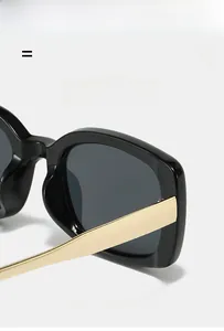 Close-up of stylish square sunglasses with glossy black frames and gold metal temples