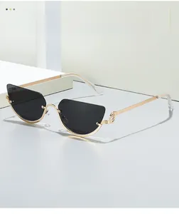 Detailed close-up of dark cat-eye lenses with slim gold metal temples on a white block