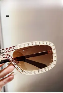 Détail de lunettes de soleil ovales avec strass brillants et verres dégradés marron