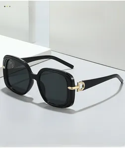 Detail of square black sunglasses showing shiny resin frames and gold metal hinges