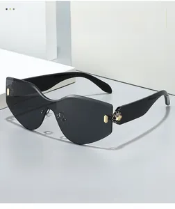 Detail of rimless sunglasses with wavy black lenses and golden hexagon accents