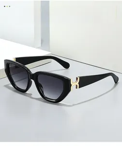 Détail de lunettes de soleil œil-de-chat noires avec charnière métallique en H doré