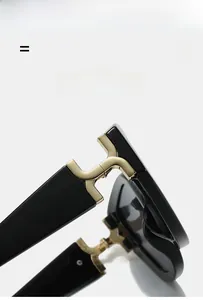 Détail des lunettes de soleil noires avec charnière métallique en forme de H dorée