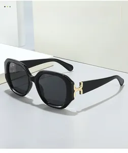 Close-up of golden H-shaped metal hinge detail on trendy black square oversized sunglasses