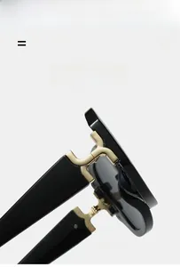 Detail of square sunglasses showing the gold metal hinge and high-gloss black frame texture