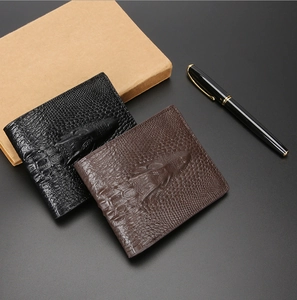 Close-up of crocodile-embossed men's wallets in black and brown with business props