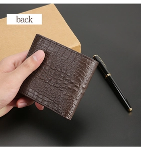 Detail view of brown crocodile texture wallet held by hand with a pen background