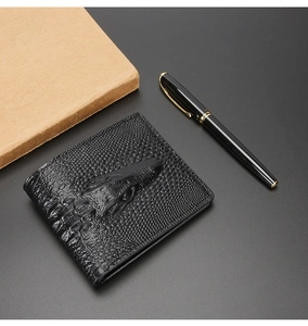 Detail of black men's wallet with 3D crocodile head relief on faux leather surface