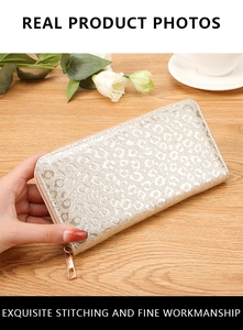 Long women's zip wallet with metallic leopard embossing on a warm wooden background