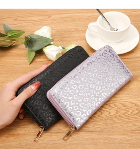 Close-up of leopard embossed wallets in black and lavender on a wooden table with decor