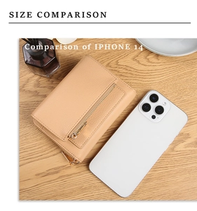 Compact beige leather wallet size comparison with iPhone 14 on a wooden desk