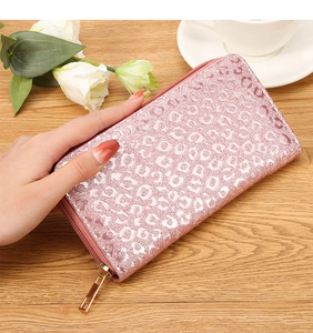 Pink leopard print glitter wallet being held in a stylish lifestyle cafe setting