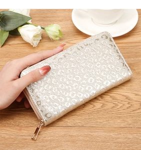 Detail of elegant gold leopard embossed wallet on a wooden table with white roses