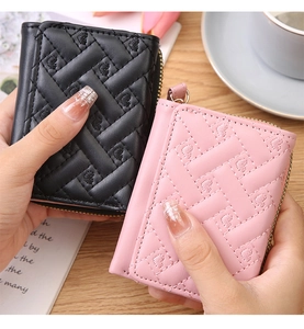 Detail of mini quilted coin purse with heart embroidery and gold zipper on wooden surface