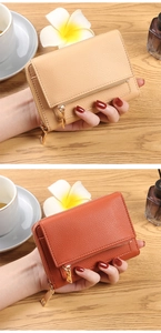 Detailed view of beige and orange lychee leather wallets with gold zippers on a desk