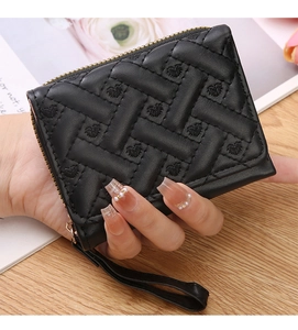 Mini black quilted coin purse with heart embroidery and hand strap shown held by hand