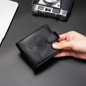 Detail of bifold men's black PU leather wallet featuring embossed eagle and snap closure