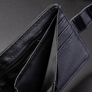 Détail d'un portefeuille en cuir noir avec fentes pour cartes et compartiment zippé en métal