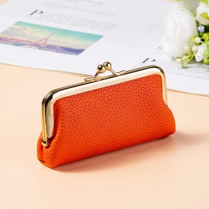 Detail of an orange litchi-grain leather mini pouch with gold metal clasp closure