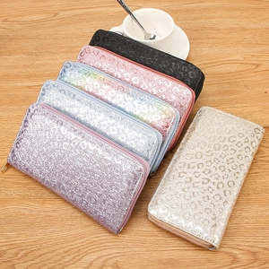 Long leopard embossed zip wallets in various metallic colors on a wooden surface