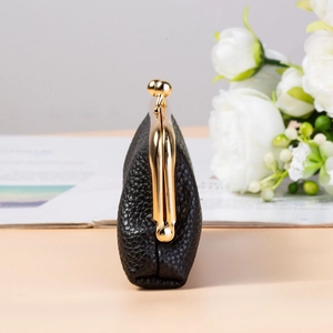Detailed side view of black lychee grain leather purse with golden metal clasp closure