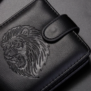Macro detail of lion head embossed pattern on vintage black leather wallet with stitching