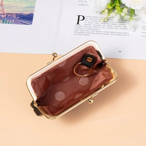 Detailed view of mini coin purse with polka dot lining and internal gold key ring