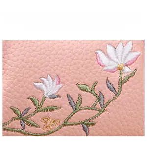 Close-up of pink lychee leather with detailed floral embroidery and golden thread accents