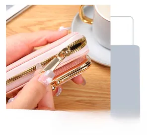 Close-up of smooth golden zipper and pink litchi grain leather on a mini wallet