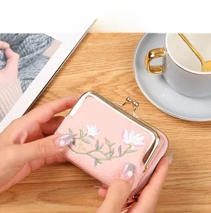 Close-up of pink mini wallet with lychee leather texture and white floral embroidery