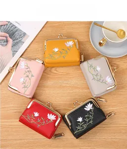 Flat lay of five mini floral embroidered wallets in diverse colors on a wooden table