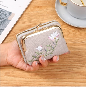 Detail of grey floral embroidery wallet with vintage metal clasp held by hand