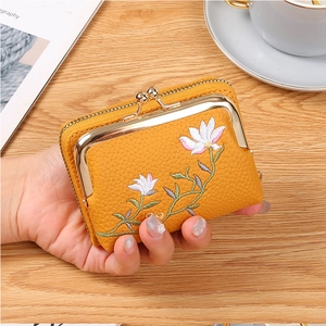 Close-up of yellow leather mini coin purse with floral embroidery and gold kiss-lock