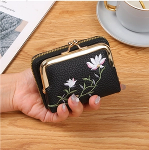 Close-up of black leather coin purse with flower embroidery and metal frame closure