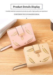 Detail of short leather wallets with leaf cutout pattern and metal leaf pendant on wood