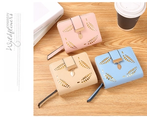 Detail of short PU leather wallets with leaf cutout design and metal leaf pendant charms