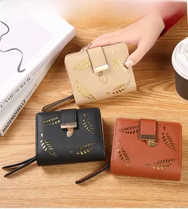 Three-color leaf cutout short wallets in beige black and caramel on a wooden surface