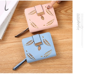 Close-up of pink and blue short wallets with hollow leaf patterns on a wooden desk