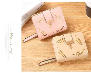 Detail of pink and beige short wallets featuring laser-cut leaf pattern and metal pendants