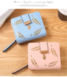Detail of short leather wallets with leaf hollow design and metal pendant charms