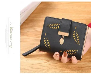 Detail of black pebbled leather wallet with hollow leaf design and gold metal charm