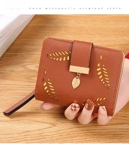 Detail of caramel women's bifold wallet with leaf cutout design and gold leaf pendant