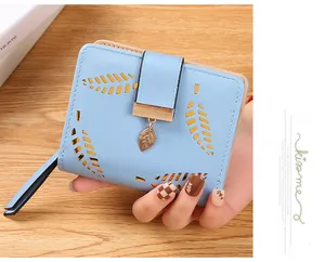 Detail of light blue leaf-patterned bifold wallet with hollow-out design and gold pendant