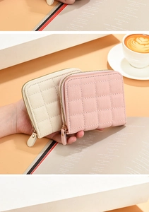 Détail de portefeuilles compacts en cuir matelassé avec zips dorés en crème et rose
