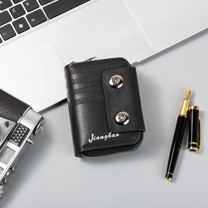 Detail of black leather wallet with double snap buttons and side zipper in office setting