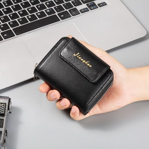 Dettaglio di un porta carte in pelle nera con logo dorato e chiusura a zip
