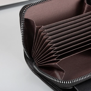 Close-up of black leather card holder featuring brown accordion style slots and metal zipper