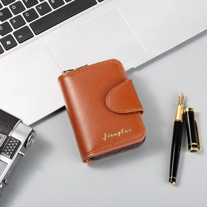 Detailed view of a brown leather wallet with zipper and gold logo on office desk